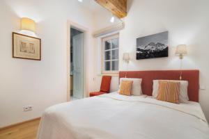 a bedroom with a white bed and a red headboard at Bacherwiese Penthouse by Alpine Host Helpers in Kitzbühel