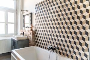 ein Bad mit einer Badewanne und einer Fliesenwand in der Unterkunft Stylishly redecorated apartment in great location in Budapest