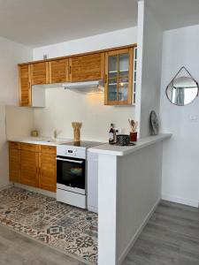 une cuisine avec des placards en bois et un comptoir blanc dans l'établissement Appartement au cœur de la station de Super-Besse, à Besse-et-Saint-Anastaise