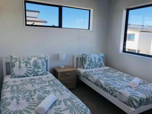 Un dormitorio con dos camas y una ventana. en Modern & Luxurious Home 3, en Auckland