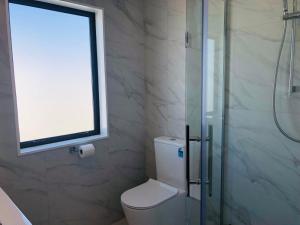 baño con ducha y aseo con ventana en Modern & Luxurious Home 3, en Auckland 9 fotos más