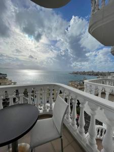 een balkon met een tafel en stoelen en de oceaan bij Seaside Apartmens Sarande in Sarandë