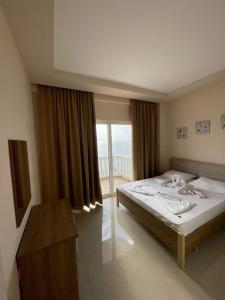 een slaapkamer met een bed en een groot raam bij Seaside Apartmens Sarande in Sarandë