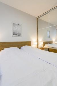 sypialnia z dużym białym łóżkiem i lustrem w obiekcie Nadmorskie Tarasy w Kołobrzegu Apartament B501 w Kołobrzegu