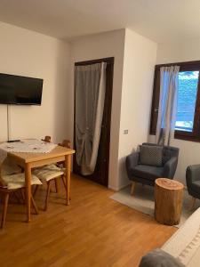 Appartamento a 2,5 km da Alleghe في أليغي: غرفة معيشة مع طاولة وكراسي وتلفزيون