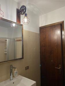 La salle de bains est pourvue d'un lavabo, d'un miroir et d'une porte en bois. dans l'établissement Appartamento a 2,5 km da Alleghe, à Alleghe