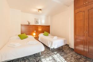 2 bedden in een kamer met witte lakens en groene kussens bij Villa Julia in Rubí