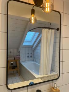 a mirror in a bathroom with a bath tub at Gemütliches Loft in Geretsried