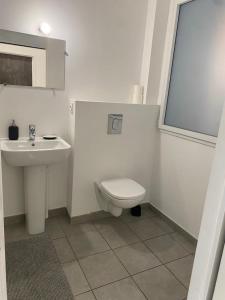 La salle de bains blanche est pourvue de toilettes et d'un lavabo. dans l'établissement @Coloc Gîtes urbains, à Nantes