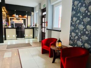 a restaurant with red chairs and a table and a counter at Hotel Elda in Bydgoszcz