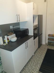 kuchnia z białymi szafkami i czarną lodówką w obiekcie LOVE Appartement partagé avec le proprietaire w mieście Saint-Louis