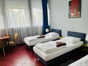 two beds in a room with a table and window at Hotel Elda in Bydgoszcz