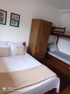 a bedroom with two beds and a wooden cabinet at Cantinho Feliz a 900m do Capivari in Campos do Jordão