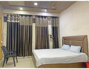 ein Schlafzimmer mit einem Bett, einem Stuhl und Vorhängen in der Unterkunft Satkar Homestay, Saharanpur in Saharanpur