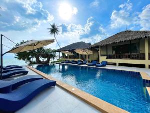 una piscina con sillas y sombrillas azules en Absolute Beachfront Villas en Baan Tai