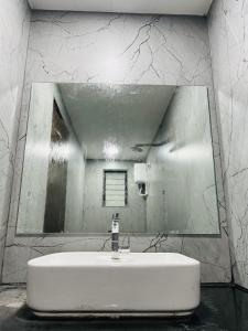 ein weißes Badezimmer mit einem Spiegel und einem Waschbecken in der Unterkunft Hotel New City Light in Surat