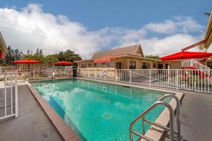 una piscina en un complejo con sombrillas rojas en Econo Lodge Hollywood - Ft Lauderdale International Airport en Hollywood