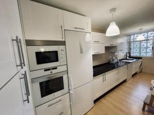 een keuken met witte kasten en een witte koelkast bij Elegante, Bonito, Buenas Vistas y cerca de La Nogalera in Torremolinos