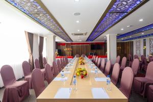 una mesa larga en una habitación con sillas rosas en Pearl Beach Hotel Quy Nhon, en Quy Nhon