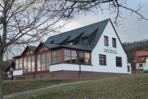 une grande maison blanche avec un toit noir dans l'établissement Träbeser Bauernstube, à Meiningen