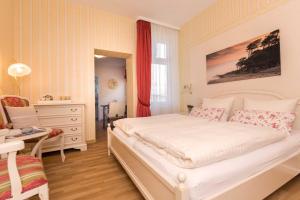 a bedroom with a large white bed and a desk at Pension Arielle _ Objekt 28014 in Warnemünde