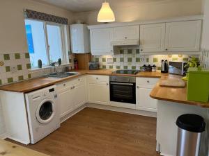 a kitchen with white cabinets and a washing machine at Spacious home near Glasgow Green in Glasgow