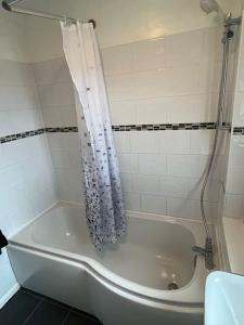 El baño incluye bañera blanca con cortina de ducha. en Spacious home near Glasgow Green en Glasgow