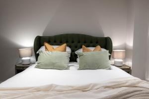 a bed with white sheets and pillows with two lamps at Three Bedroom Apartments near Spitalfields Market and Tube Station in London