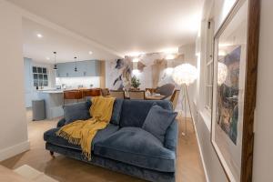 a living room with a blue couch and a kitchen at Three Bedroom Apartments near Spitalfields Market and Tube Station in London