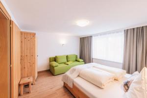 ein Schlafzimmer mit einem Bett und einem grünen Sofa in der Unterkunft Landhaus Aggenstein in Haldensee