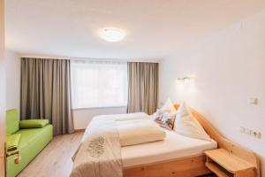 ein Schlafzimmer mit einem großen Bett und einem grünen Stuhl in der Unterkunft Landhaus Aggenstein in Haldensee