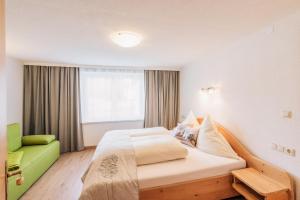 a bedroom with a large bed and a green chair at Landhaus Aggenstein in Haldensee