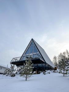 a building with a triangular roof in the snow at Altai Palace Hotel in Manzherok