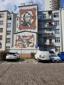 dois carros estacionados em frente a um edifício com um grande mural em NowyŚwiat.2 min doTheChopinUniwersity of Music. em Varsóvia