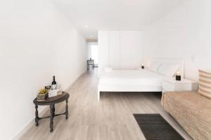 ein weißes Schlafzimmer mit einem weißen Bett und einem Tisch in der Unterkunft OPO - Fantastic studio with garden in Porto