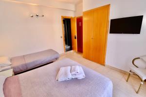 a bedroom with two beds and a flat screen tv at Hotel Ibiza in Sitges