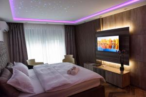 una camera con un grande letto e una TV a parete di Perla Lux apartmani a Inđija