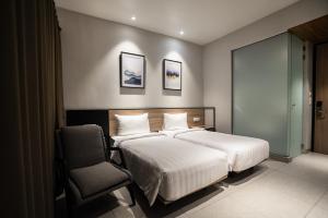 een hotelkamer met 2 bedden en een stoel bij CONJIOO HOTEL at JAKARTA AIRPORT in Tangerang