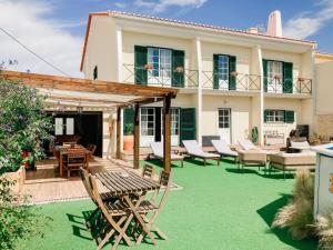 a house with a green yard with a table and chairs at In My House Baleal in Baleal