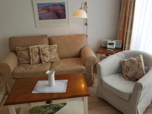 uma sala de estar com um sofá e uma mesa em Sylter-Besserburg-App-12 em Westerland