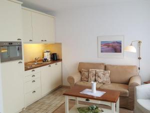 uma sala de estar com um sofá e uma cozinha em Sylter-Besserburg-App-12 em Westerland