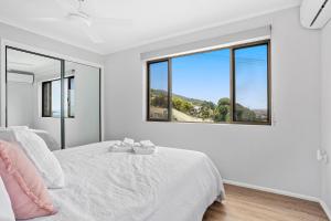 una camera bianca con letto e finestre di Freeman Retreat Yeppoon a Yeppoon