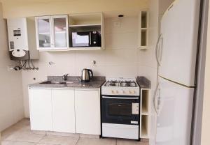 a small kitchen with a stove and a refrigerator at Departamento con cochera Mar del Plata in Mar del Plata