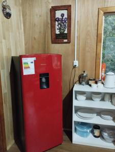 einem roten Kühlschrank neben einem weißen Regal in der Unterkunft Cabañita Sustentable El Este Cochamó in Cochamó