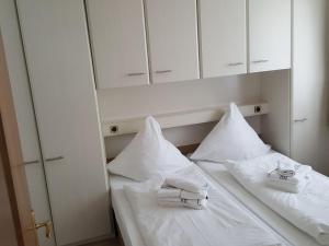 un letto bianco con cuscini e asciugamani bianchi di Sylter-Besserburg-App11 a Westerland