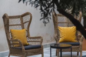 2 sillas de mimbre con almohadas amarillas y mesa en CASA PALACIO SUR II, en El Puerto de Santa María