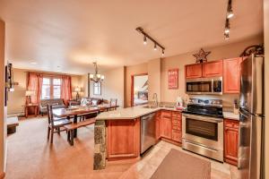 a kitchen with wooden cabinets and a dining room with a table at Zephyr Slopeside - 1504 condo in Winter Park