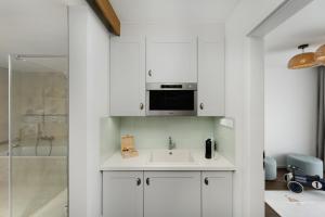 a white kitchen with a sink and a microwave at Mövenpick Balaland Resort Lake Balaton in Szántód