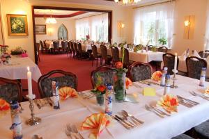 uma sala com mesas e cadeiras com toalhas de mesa brancas em Hotel Graf Balduin em Esterwegen
