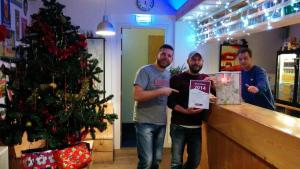 Tre uomini in piedi al bancone con un albero di Natale di 3BE Backpackers Bed & Breakfast Eindhoven a Eindhoven